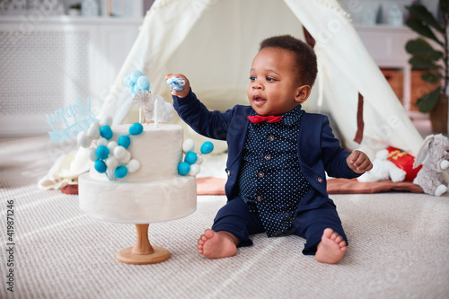 Photography cute one year old baby boy having a home party with birthday cake