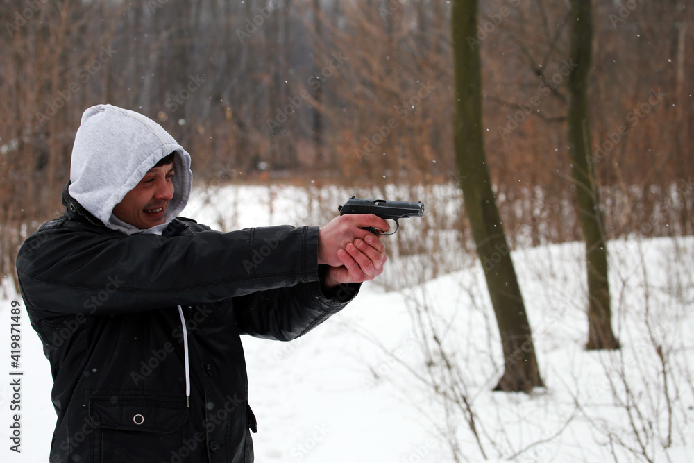 Man shooting with a pistol in the forest in winter