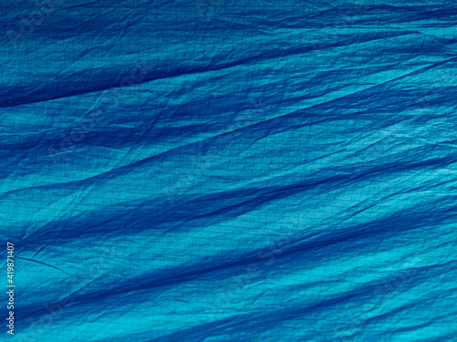 Blue abstract wrinkled fabric background with copy space, view from above