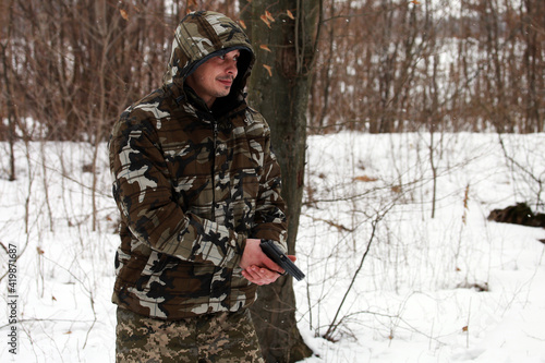 Soldier shooting with a pistol in the forest in winter