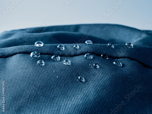 Water drops on waterproof membrane fabric. Detail view of texture of blue waterproof cloth.