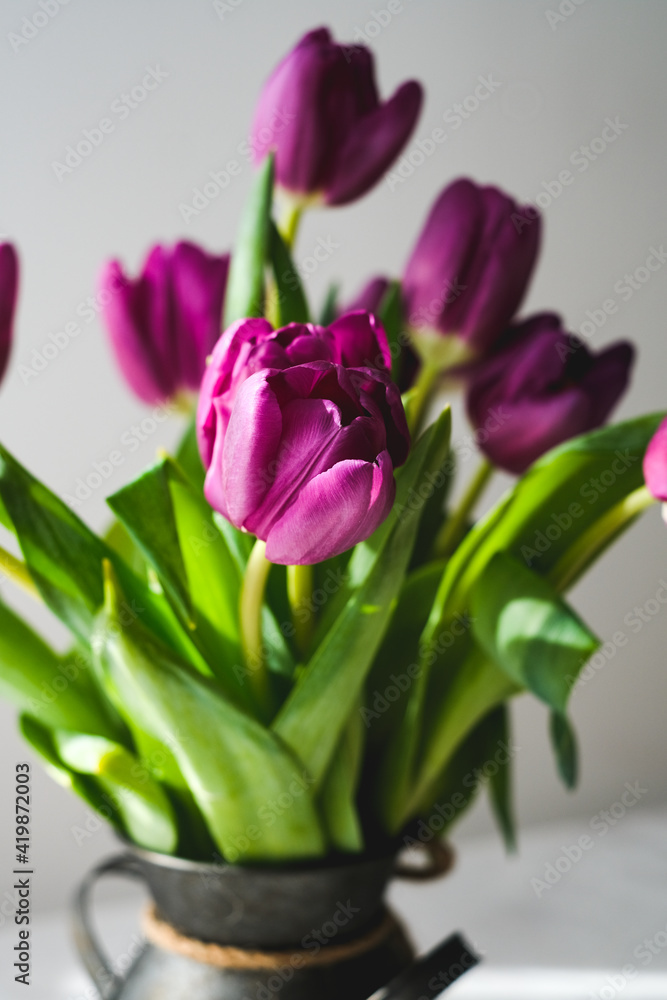Lilac purple tulip flowers on table. Spring bouquet flowers in vintage vase. Floral concept. Floral background. White decoration and light background Lilac purple tulip flowers on table. Spring bouquet flowers in vintage vase. Floral concept. Floral background. White decoration and light background