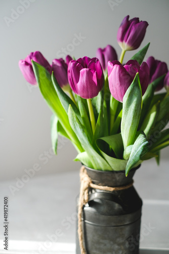 Lilac purple tulip flowers on table. Spring bouquet flowers in vintage vase. Floral concept. Floral background. White decoration and light background