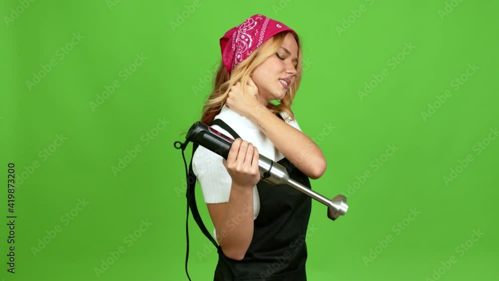 Young blonde girl using hand blender with neck pain over isolated background on green screen chroma key Young blonde girl using hand blender with neck pain over isolated background on green screen chroma key