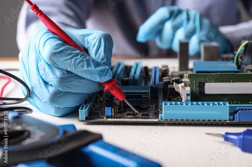 Technician repairing electronic circuit board at table, closeup