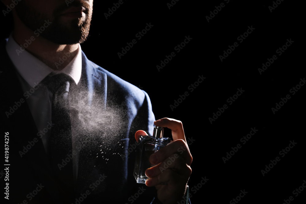 Man spraying luxury perfume on black background, closeup - obrazy, fototapety, plakaty 
