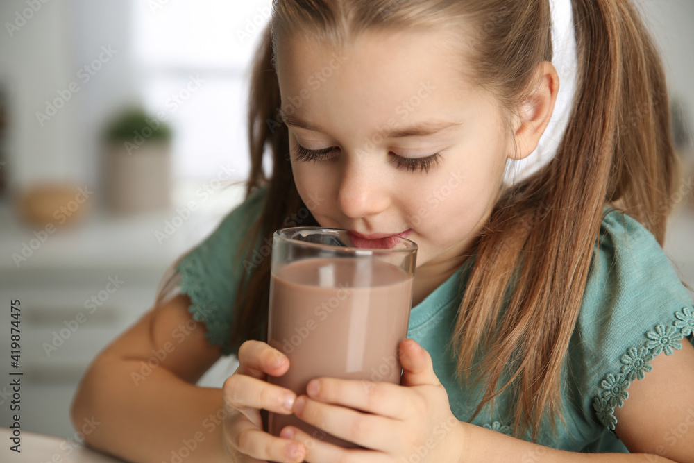 Cute little child drinking tasty chocolate milk in kitchen, closeup Cute little child drinking tasty chocolate milk in kitchen, closeup