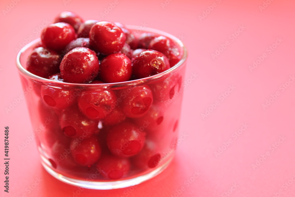 cherry in a glass on a pink red background with a place to text the view from the side close-up of the copyspace cherry in a glass on a pink red background with a place to text the view from the side close-up of the copyspace