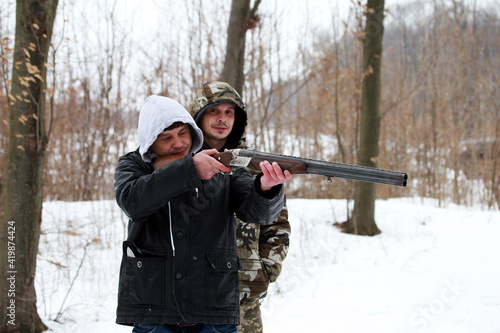 Twin brothers with a shotgun in the winter forest