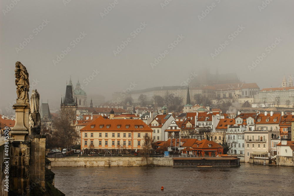 Fototapeta premium Postcard view of Prague Castle in mist from Charles Bridge,Czech republic.Famous tourist destination.Prague panorama.Foggy morning in city.Amazing European cityscape.Inversion weather outdoors.