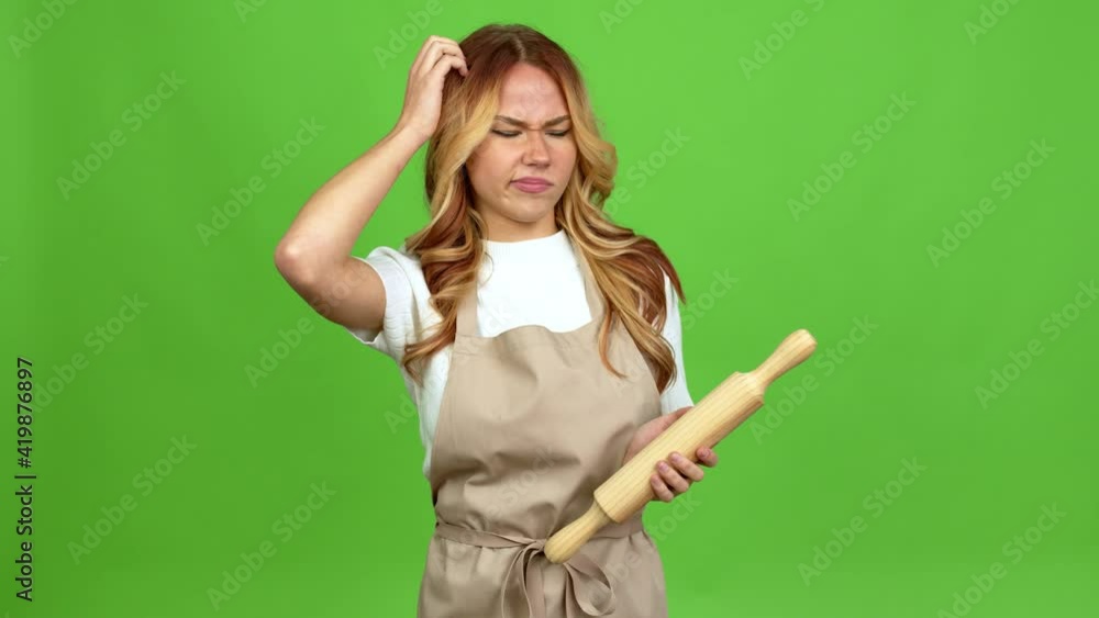 Young blonde girl holding a rolling pin having doubts while scratching head over isolated background on green screen chroma key Young blonde girl holding a rolling pin having doubts while scratching head over isolated background on green screen chroma key