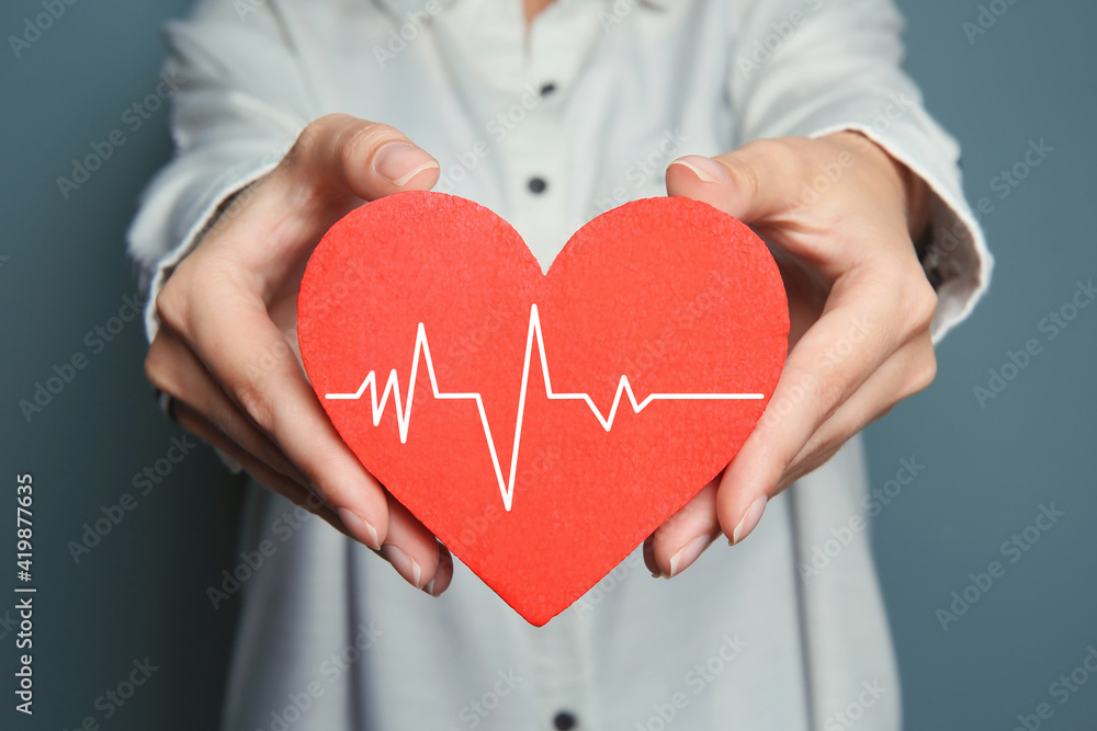 Woman holding red heart with cardiogram, closeup Woman holding red heart with cardiogram, closeup