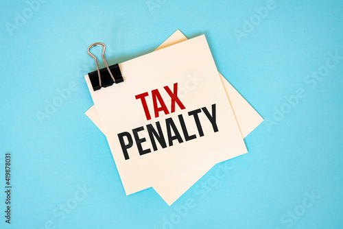 Text TAX PENALTY on sticky notes with copy space and paper clip isolated on red background.Finance and economics concept.