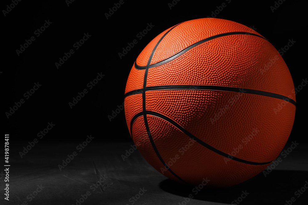 Basketball ball on grey stone table against dark background, space for text Basketball ball on grey stone table against dark background, space for text