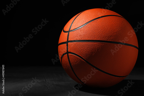 Basketball ball on grey stone table against dark background, space for text © New Africa