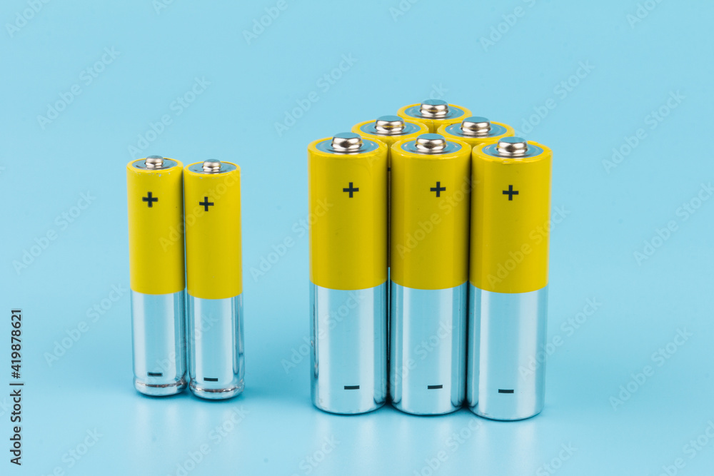 Photo of gray-yellow alkaline AA batteries on blue background. Recycling of rechargeable NiMH batteries. The most popular size of accumulators. Copy space. Photo of gray-yellow alkaline AA batteries on blue background. Recycling of rechargeable NiMH batteries. The most popular size of accumulators. Copy space.