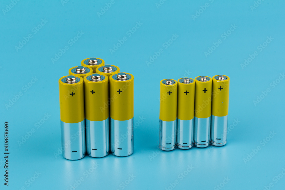 Photo of gray-yellow alkaline AA batteries on blue background. Recycling of rechargeable NiMH batteries. The most popular size of accumulators. Copy space. Photo of gray-yellow alkaline AA batteries on blue background. Recycling of rechargeable NiMH batteries. The most popular size of accumulators. Copy space.