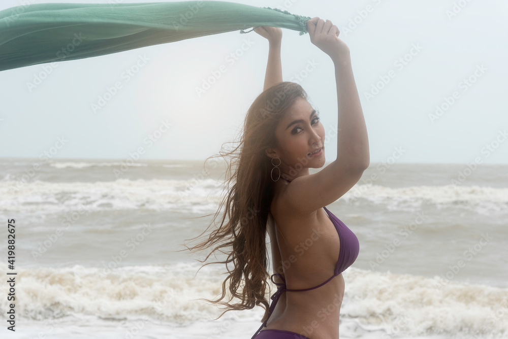Beautiful asian woman in swimsuit bikini at the beach by the sea. Wind blow  from the sea feel good. Stock Photo | Adobe Stock