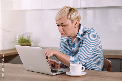 Focused serious woman working on laptop at home Female using portable computer