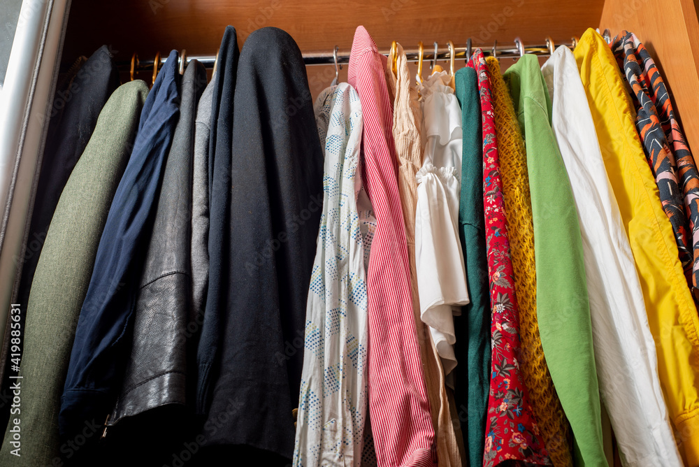Organizing a variety of clothes in a wardrobe. Clothes on hangers in dark and light colors. Separation of men's and women's wardrobe Organizing a variety of clothes in a wardrobe. Clothes on hangers in dark and light colors. Separation of men's and women's wardrobe