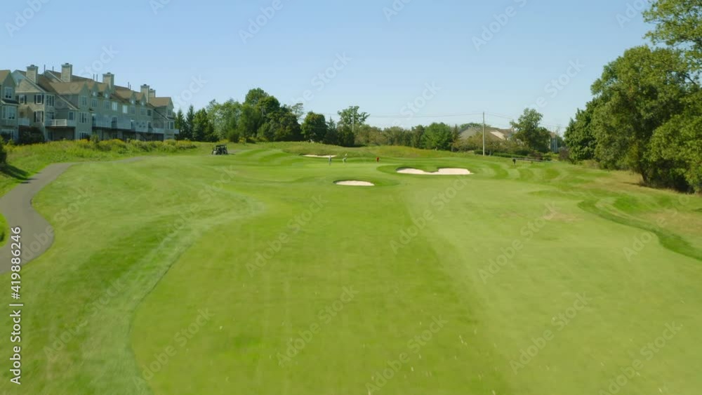 Golf course flyover with fairway green sand traps and golf cart Golf course flyover with fairway green sand traps and golf cart