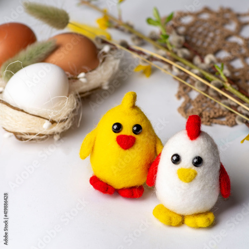 Easter chickens and hens made of wool on the background of Easter decor and a white background. Wool decor for home decoration © smirart