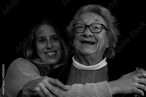 Family portrait of elderly 80s woman hugging young grand daughter.Black and white photography of happy people smiling concept lifestyle.