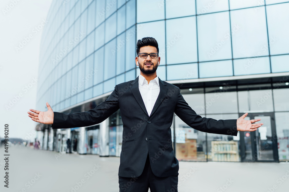Successful Indian man in a black suit, behind him a large modern building, business owner, boss Successful Indian man in a black suit, behind him a large modern building, business owner, boss
