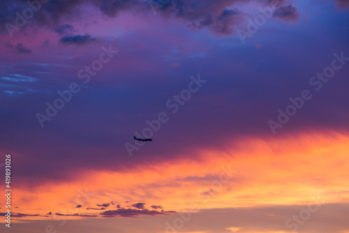 Horizontal view of plane flying above sunset with dramatic coloured sky, Montreal, Quebec, Canada