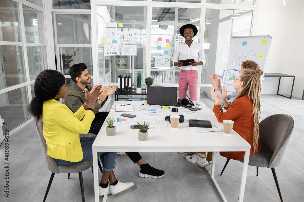 Young creative multiracial colleagues clapping in hands during meeting Young creative multiracial colleagues clapping in hands during meeting