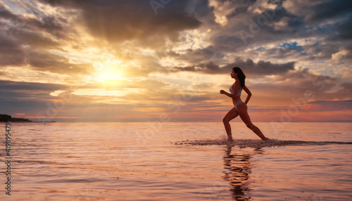 Young beautiful sexy fit lingerie brunette model running in the water at dramatic sunset 