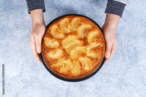 Man holding baked apple pie in hands on white background