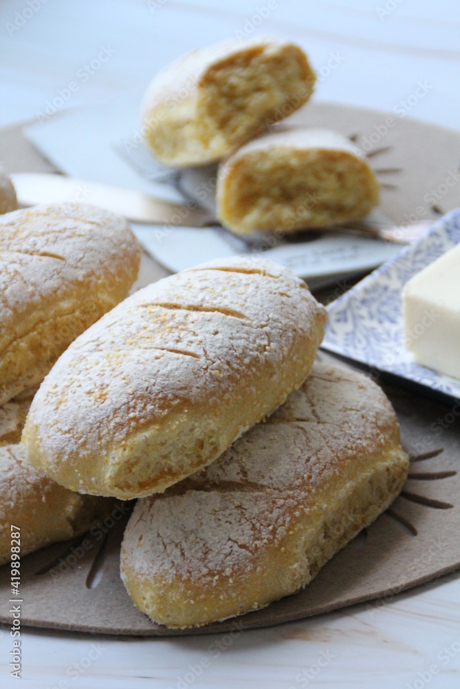 fresh cornmeal buns, butter on a plate, flour-sprinkled buns, fresh bread, homemade baked goods fresh cornmeal buns, butter on a plate, flour-sprinkled buns, fresh bread, homemade baked goods