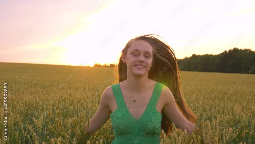 A beautiful girl with long hair in a green dress runs through a wheat field. Happy girl enjoys freedom, fresh air, dreams. A healthy lifestyle. Countryside. A beautiful girl with long hair in a green dress runs through a wheat field. Happy girl enjoys freedom, fresh air, dreams. A healthy lifestyle. Countryside.