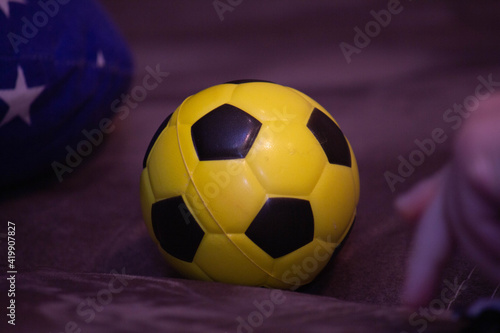 Yellow soccer ball lies on the couch 