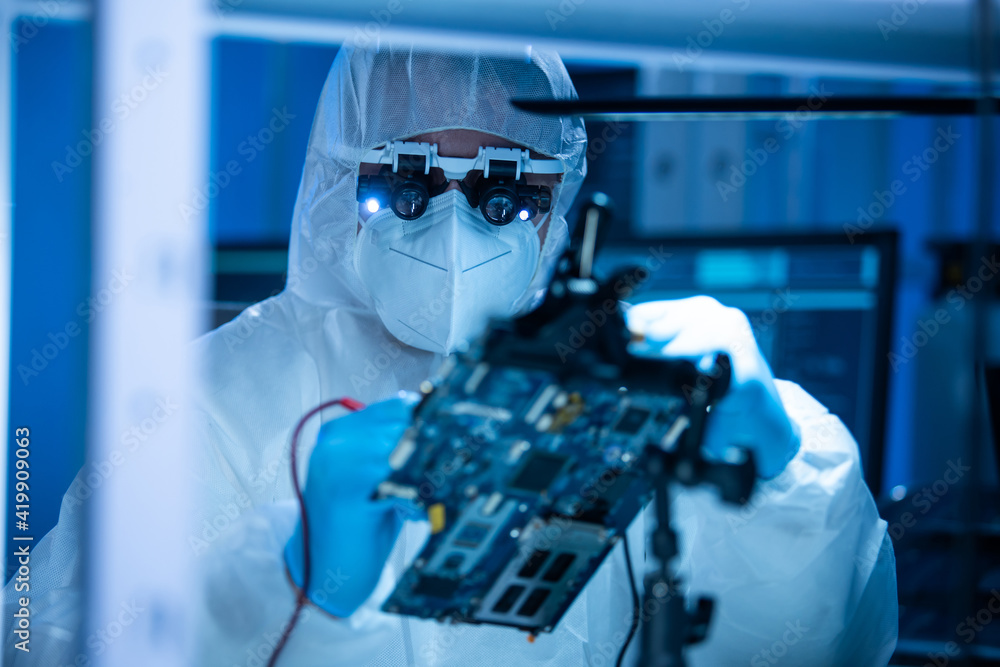 Microelectronics engineer works in a modern scientific laboratory on computing systems and microprocessors. Electronic factory worker is testing the motherboard and coding the firmware.