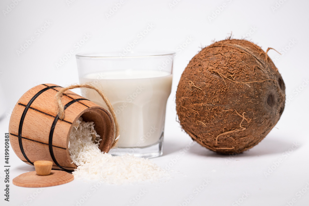 fresh coconut near wooden bowl with coconut flakes and glass of coco milk. isolated on white background. tropical nut fresh coconut near wooden bowl with coconut flakes and glass of coco milk. isolated on white background. tropical nut