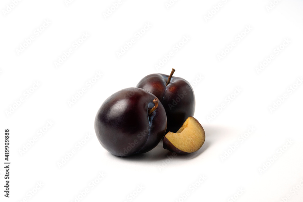 Fototapeta premium Whole and sliced black cherry plums on white background