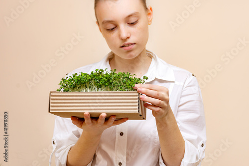 vegetarian woman holding an eco box made of organic micrograms of mustard sprouts. Growing sprouts. Organic products. Blurred focus on a woman face. photo