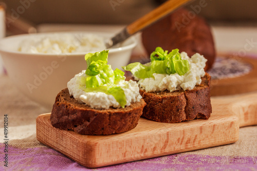 Topped rye bread, bowl with cottage cheese. Healthy food idea. Side view