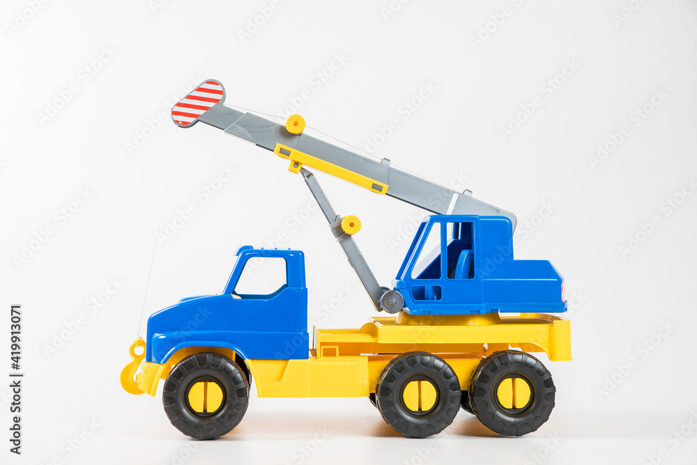 Plastic car. Toy model isolated on a white background. Yellow-blue truck crane with an arrow to lift the load.