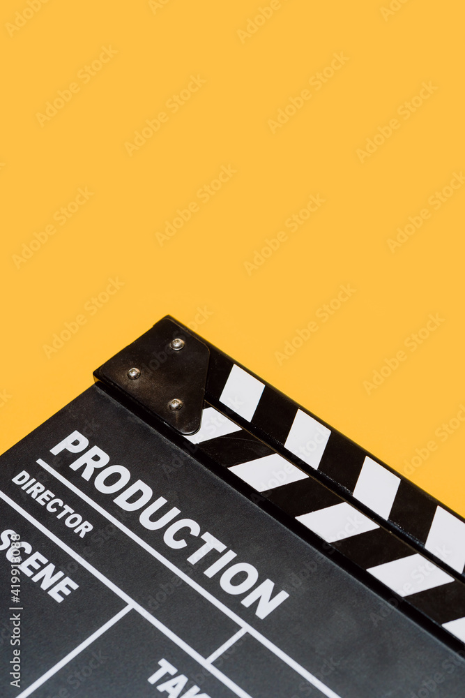Film clapperboard on yellow studio background