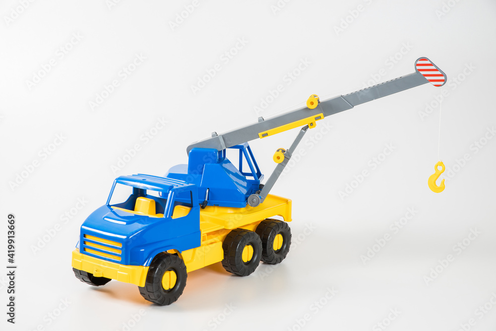 Plastic car. Toy model isolated on a white background. Yellow-blue truck crane with an arrow to lift the load.