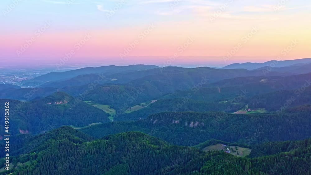 A bird's eye view of rolling mountains with green trees and distant towns A bird's eye view of rolling mountains with green trees and distant towns