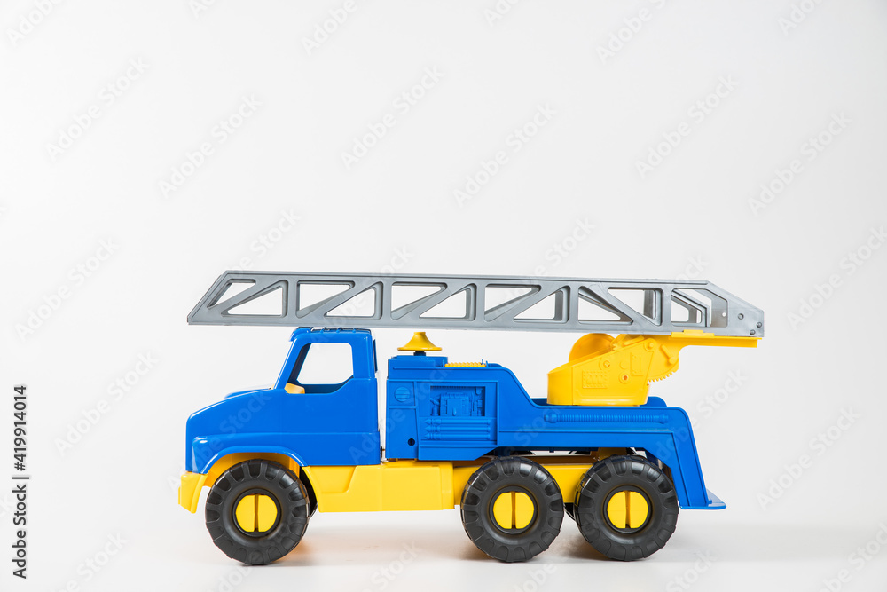 Plastic car. Toy model isolated on a white background. Yellow-blue truck with fire escape.