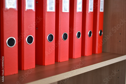 Office red folders on the shelf in the office © Lushchikov Valeriy