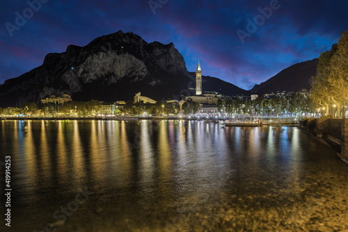 Famous holiday resort on Lake Como, Italy. City of Lecco at dusk with the lights of the promenade reflected on the lake 