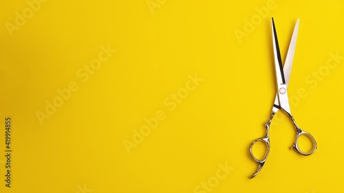 Stop motion animation template flat lay of professional hair cutting shears that cut on the spot on yellow background Hairdresser salon equipment concept with copy space Selfcare on lockdown time