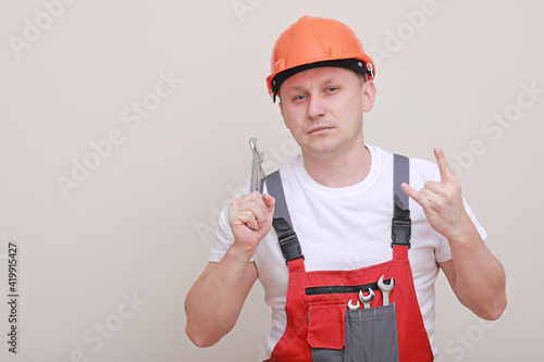 Handsome car mechanic male worker holding equipment tool, wrench standing in red uniform, safety helmet on white background. photo