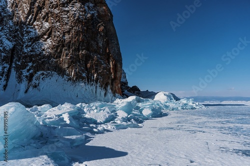 Lake Baikal in winter day. High cliffs on Olkhon Island. Large beautiful blocks of ice cover the foothills of the mountains.